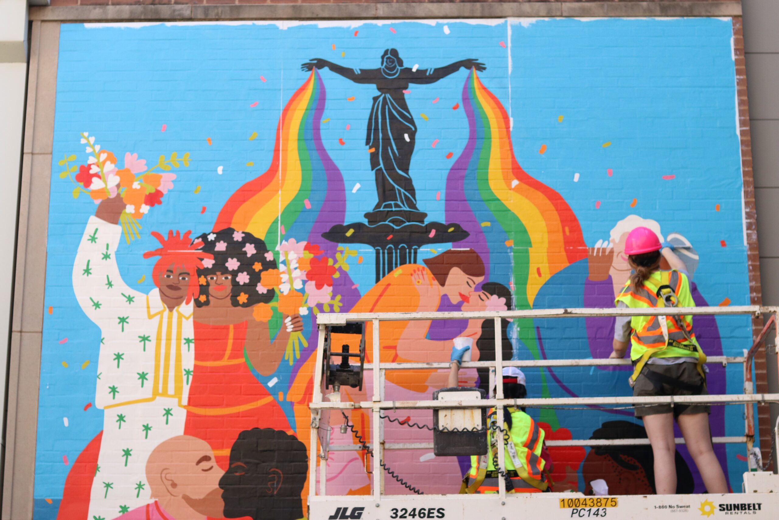 Mural studio artist installing "Fountain of Love" mural on Mercer garage