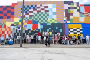 Community members and artist, william cordova, standing infront of constellation (rumi maki) mural
