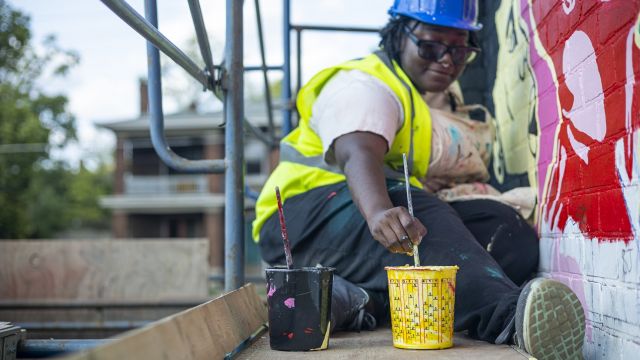 Nytaya Babbitt painting on Hear Us Out mural. Photo by MonstaTheEngineer.