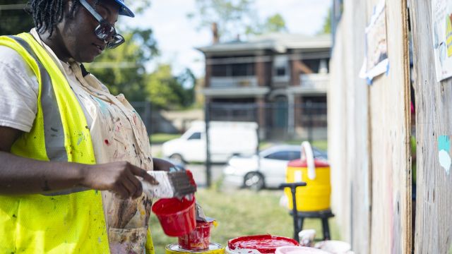 Photo of Nytaya Babbitt mixing paint at Hear Us Out mural by Monsta