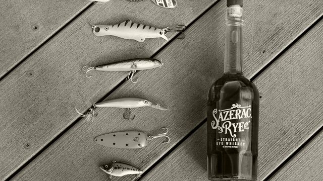 A bottle of Sazerac Rye lying next to fishing lures on a dock
